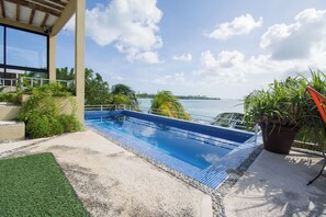 A swimming pool with a view of the water, surrounded by greenery and a building structure. - Nice house in hotel zone (Cancún)