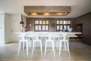 A modern kitchen with a central island, white bar stools, and large windows. - Nice house in hotel zone (Cancún)