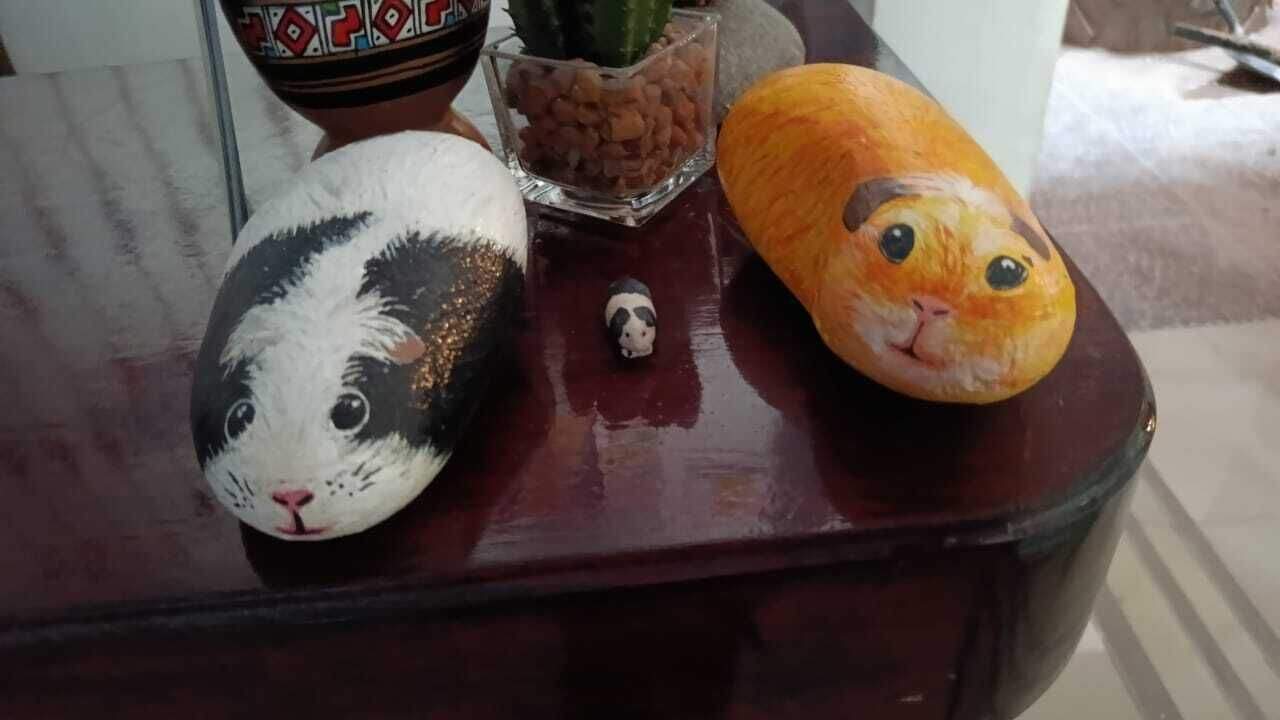 Ein Tisch mit bemalten Steinen, einer kleinen Figur und einem Glasgefäß mit Steinen.