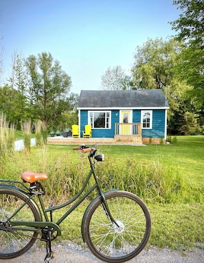 A blue house with a porch, a bicycle, and a grassy area. - Saltbox by the Bay | Views, Bikes, Vetta Spa (Waubaushene)
