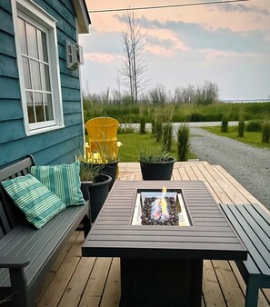 A patio with a table, chairs, a bench, and a fire feature. - Saltbox by the Bay | Views, Bikes, Vetta Spa (Waubaushene)