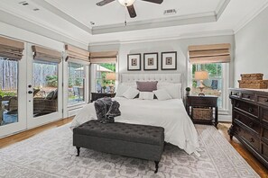 A bedroom with a large bed, a ceiling fan, a window with a view, and a dark-colored bench. - East Atlanta Retreat - Office + Backyard Oasis (Atlanta)