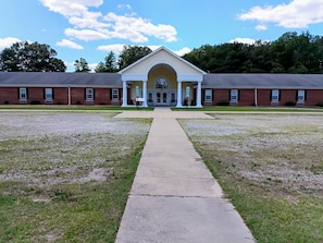 A building with a central arched entrance, flanked by two wings with windows, and a gravel courtyard. - Franklinton Center At Bricks Hotel (Whitakers)