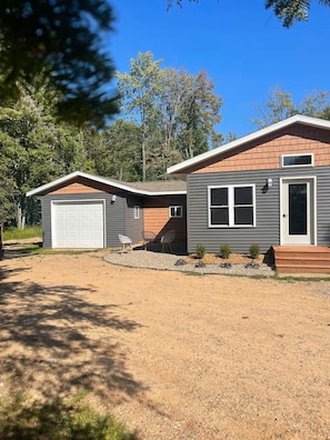 Ein zweistöckiges Haus mit Garage, überdachter Terrasse und einem kleinen Garten.