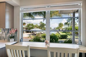 A room with a large window, a white table, and a white chair.