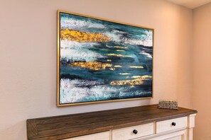 A wall-mounted abstract painting with a wooden console table below.