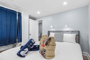 Ein Schlafzimmer mit einem Bett, einem Nachttisch, einer Lampe und einem blauen Vorhang.