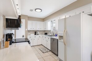 A kitchen with white cabinets, a black countertop, a dishwasher, and a refrigerator.