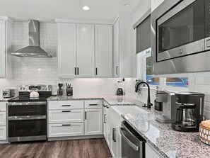 A modern kitchen with white cabinetry, stainless steel appliances, and a granite countertop.