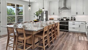 Una cocina moderna con armarios blancos, una isla grande y vistas al exterior.
