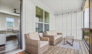 A covered patio with wicker furniture, a small table, and a view of the interior. - Sunrise Social - Modern, Views, Ping Pong, Games (Canyon Lake)