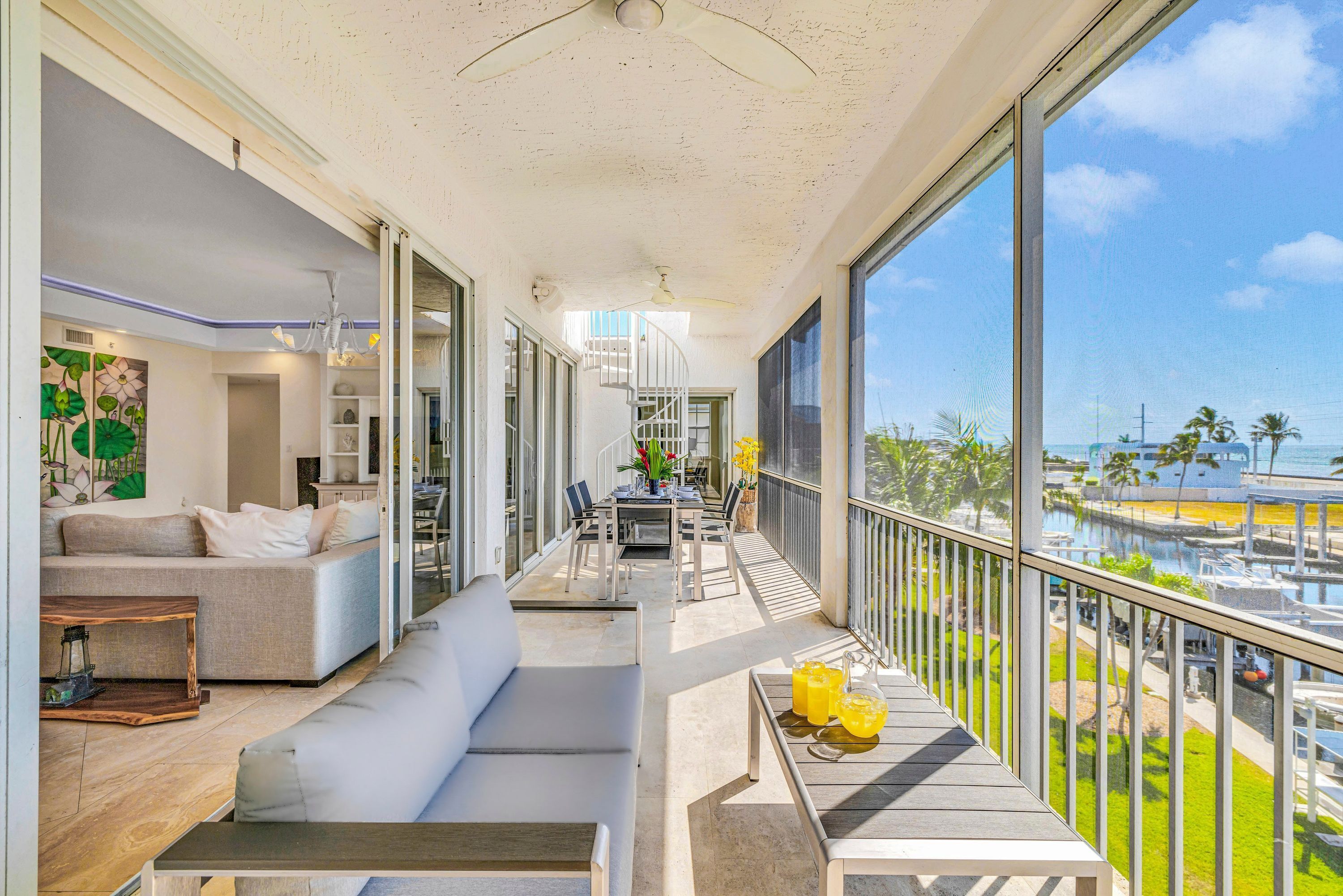 Ein modernes Wohnzimmer mit Sofa, Esstisch und einem Balkon mit Blick auf den Yachthafen.