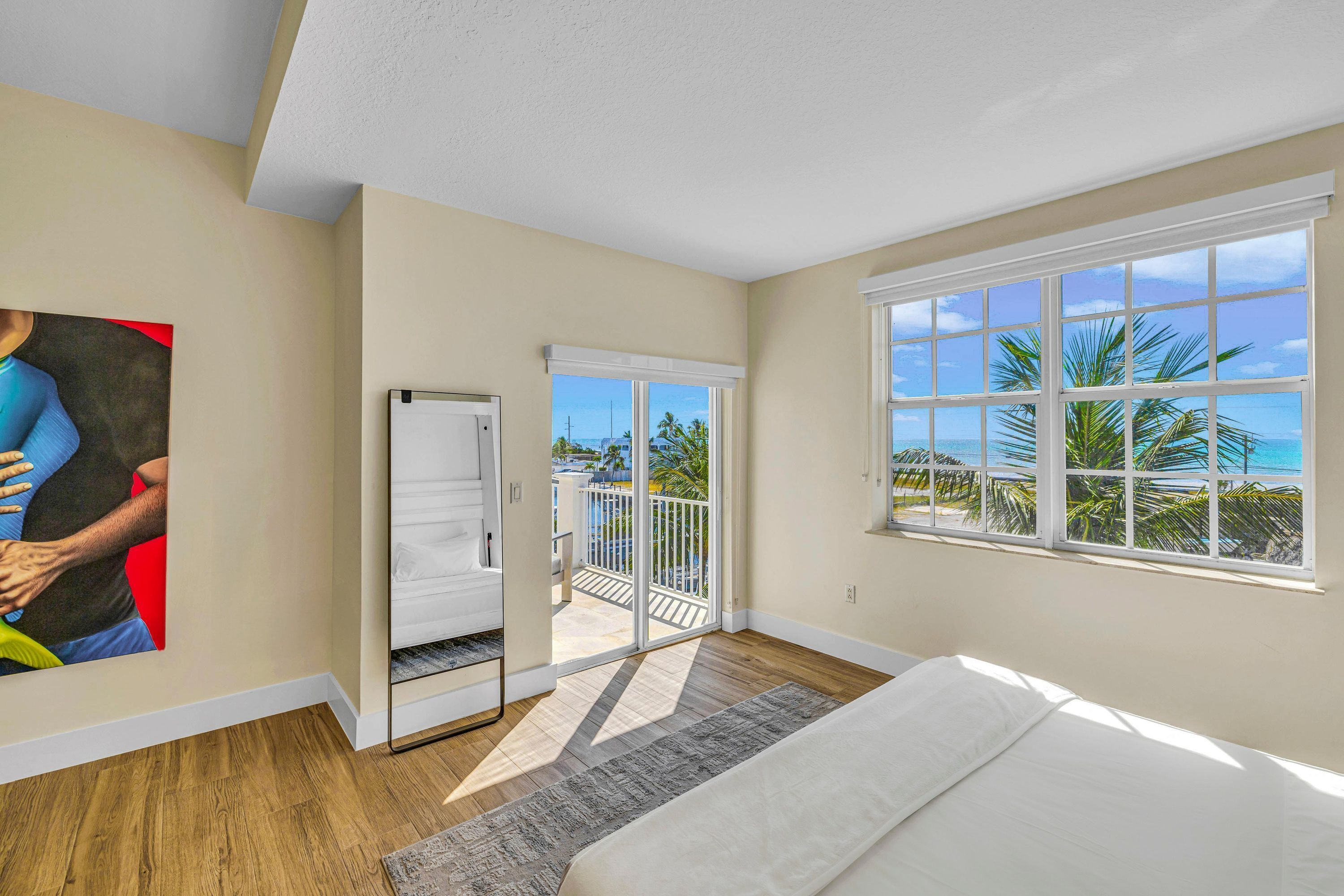Ein Schlafzimmer mit Bett, Meerblick, einer Schiebetür zu einem Balkon und einem Bild an der Wand.