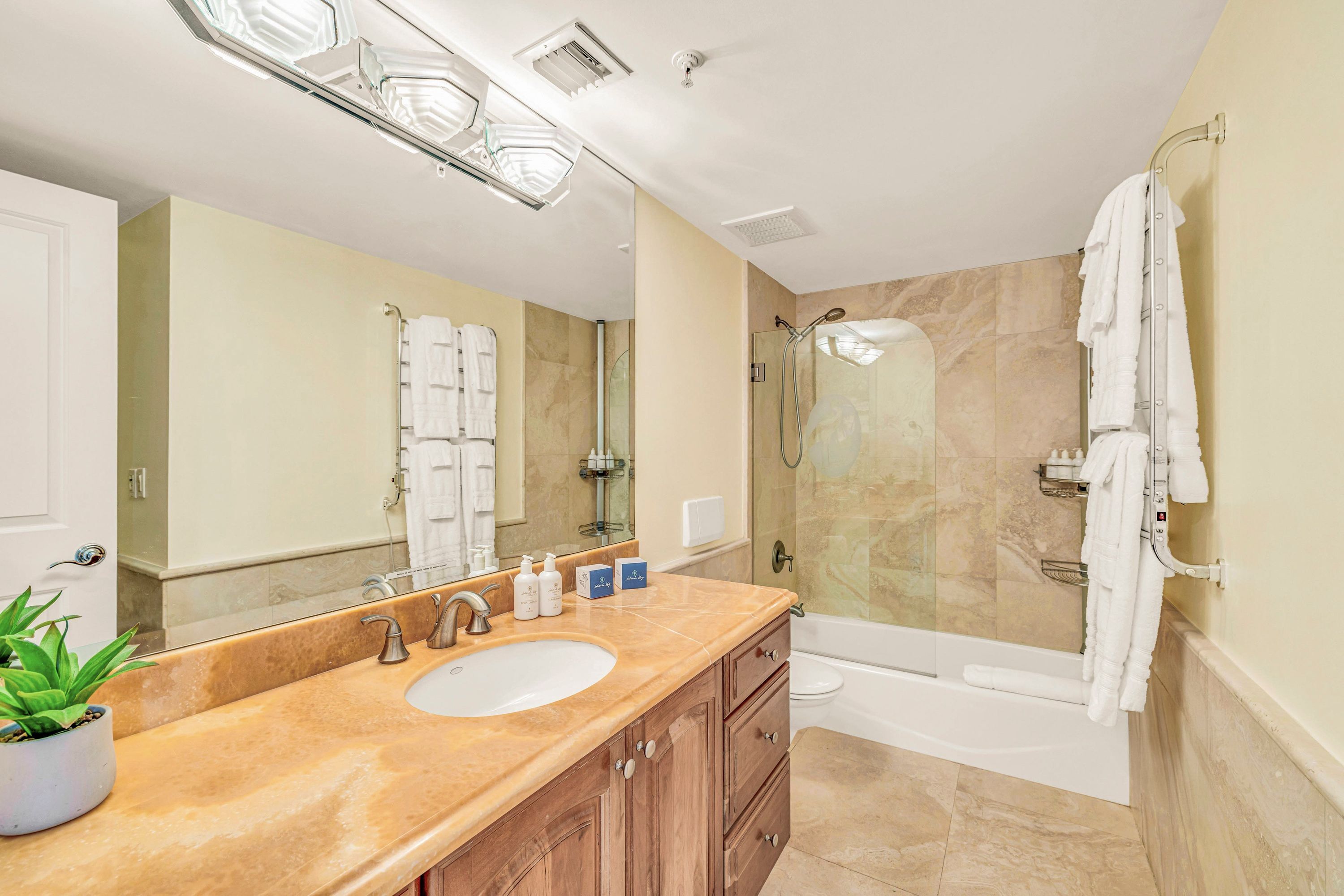 A bathroom with a sink, mirror, shower, and bathtub.