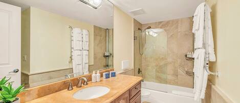 A bathroom with a sink, mirror, shower, and bathtub.
