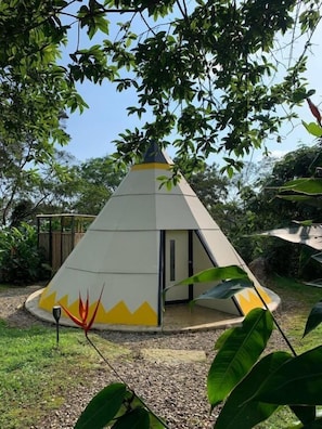 A conical structure with a door, surrounded by greenery.