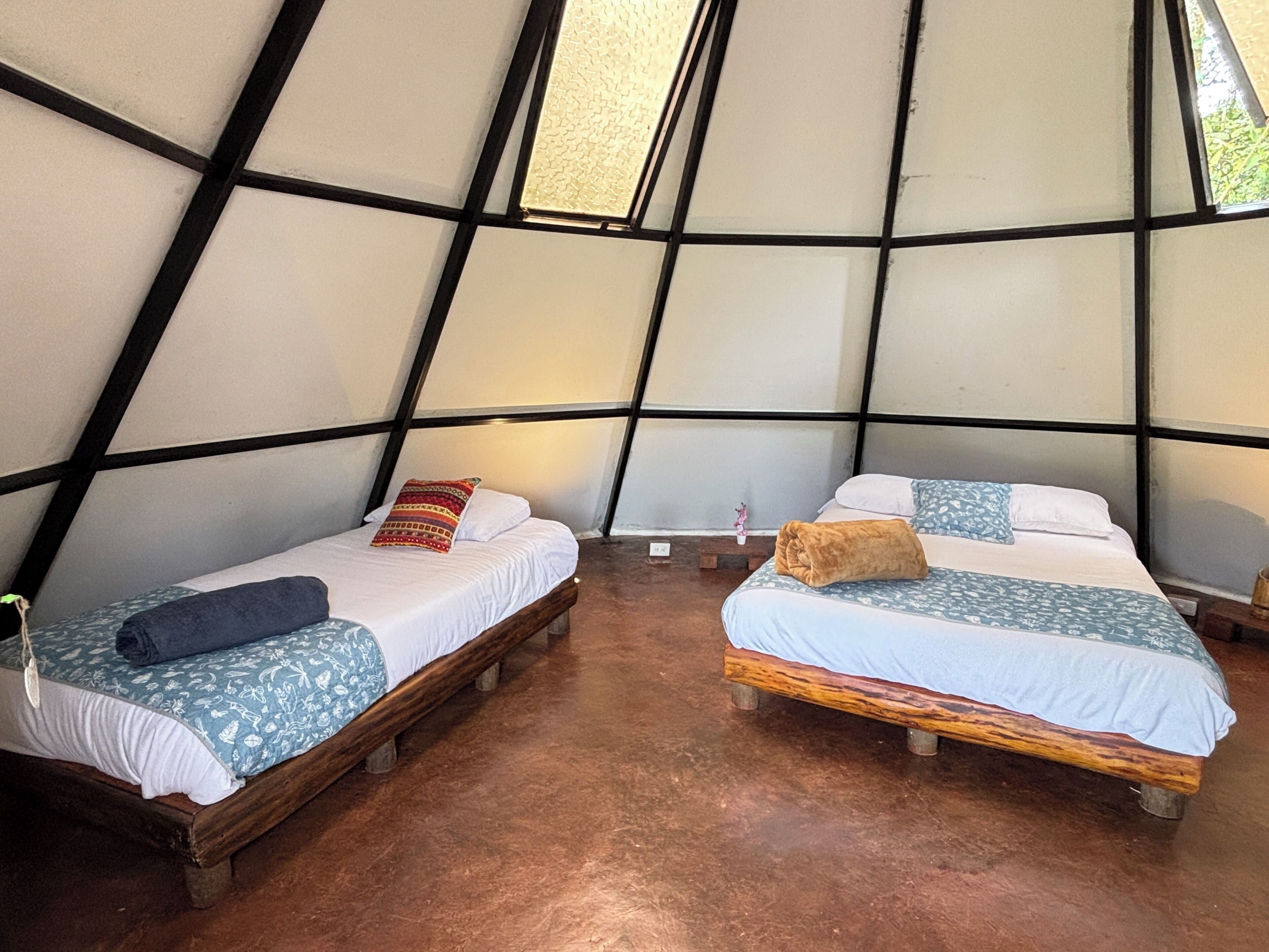 Two beds in a tent-like room with a wooden floor.