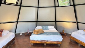 Een kamer met drie bedden, een houten vloer en een groot raam.