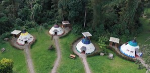 A cluster of yurts with a dirt path between them, surrounded by dense forest. - Refugio Natural Destino Payacal (La Mesa)