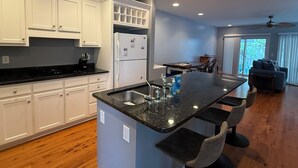Una cocina moderna con armarios blancos, encimera negra y una isla central con taburetes de bar.