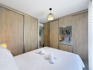 Ein Hotelzimmer mit einem Bett, einem Spiegel, einer Hängelampe und einem Holzschrank.