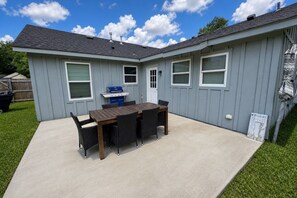 A residential building with a patio, a barbecue grill, and a dining table with chairs. - Perfect 4-bedroom mid-century home in Grand Prairie (Grand Prairie)