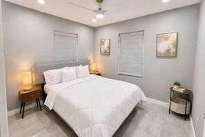 A bedroom with a bed, nightstands, a ceiling fan, and artwork on the walls. - Perfect 4-bedroom mid-century home in Grand Prairie (Grand Prairie)