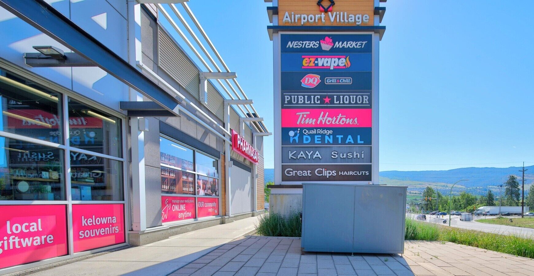 A commercial building with a sign listing various businesses including a pharmacy, a sushi restaurant, and a market.