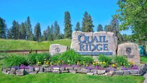 Schild für Quail Ridge Community, mit Steinbordüre und Blumenbeet.