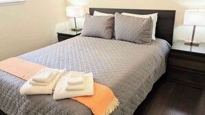 Un lit bien fait, avec une couverture matelassée, deux oreillers, une couverture pliée et un plaid à rayures.