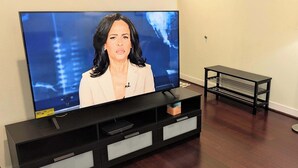 Un téléviseur posé sur un support noir, avec une console blanche en dessous.