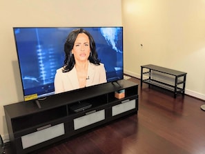 A television on a black stand with a white cabinet below it.