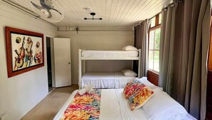 A room with bunk beds, a bed with a colorful blanket, a fan, a ceiling fan, and a painting on the wall. - Family & Group Villa - New Pool - Private Yard - Walk to the Beach (San Andrés y Providencia)