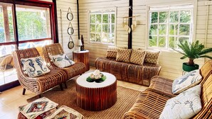 A spacious living room with wicker furniture, a ceiling fan, and large windows. - Family & Group Villa - New Pool - Private Yard - Walk to the Beach (San Andrés y Providencia)