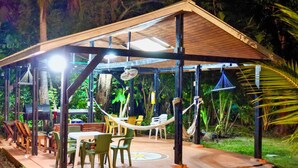 An outdoor covered patio with tables and chairs, surrounded by greenery. - Family & Group Villa - New Pool - Private Yard - Walk to the Beach (San Andrés y Providencia)