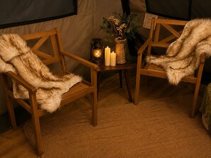 Two wooden chairs with fur throws, a lantern, candles, and a vase with flowers on a small table. - Glamping Yurt at Greeter Falls Campground (Altamont)