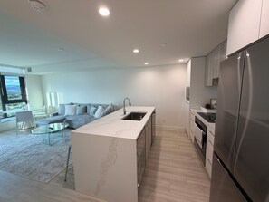 A modern kitchen with a central island, a built-in sink, and a stainless steel refrigerator.