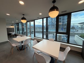 A modern conference room with large windows, white tables, and chairs.