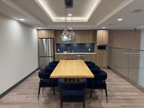 Una cocina moderna con una isla central, electrodomésticos de acero inoxidable y un comedor con mesa de madera y sillas tapizadas en azul.