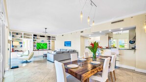 Un comedor moderno con una mesa de madera, sillas blancas y una cocina al fondo.