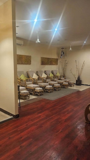 A room with wicker furniture, a wooden floor, and wall-mounted lighting.