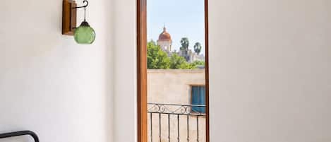 A bedroom with a bed, a nightstand, a window with a view of a building, and a ceiling fan.