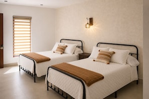 Two twin beds with headboards, a wall-mounted light fixture, and a window with blinds. - Casa Feregrino Hotel Boutique (Cuatro Ciénegas de Carranza)