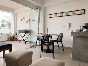 Eine moderne Küche mit einem runden Esstisch, schwarzen Stühlen, einer Kaffeemaschine und einer Weinflasche.