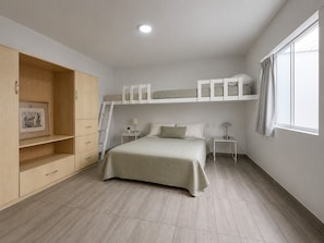 Ein Schlafzimmer mit Etagenbett, Kleiderschrank, Schreibtisch und Fenster.