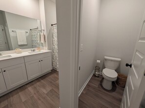 A bathroom with a white sink, mirror, and toilet. - Relax in Calabash – New 3BR/2BA Home Just Minutes to Beaches, Golf & Seafood (Calabash)