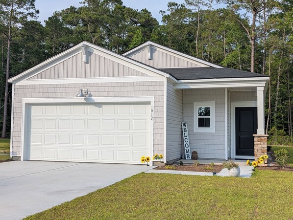 A two-story house with a garage, a welcome sign, and a mailbox. - Relax in Calabash – New 3BR/2BA Home Just Minutes to Beaches, Golf & Seafood (Calabash)