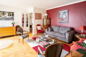 Ein Wohnzimmer mit einer Couch, Sesseln, einem Couchtisch, einem Kamin und einem Bücherregal.