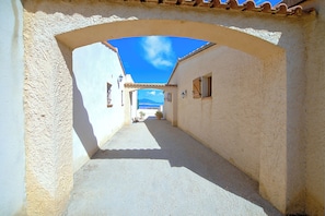 A narrow alleyway with a clear blue sky above, flanked by buildings with light-colored walls and tiled roofs. - The Terrace of the Gulf of Ajaccio - Welkeys (Pietrosella)