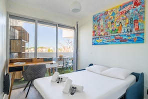 Ein Hotelzimmer mit einem Bett, einem Schreibtisch, einem Sessel, einem kleinen Tisch und einem großen Fenster.